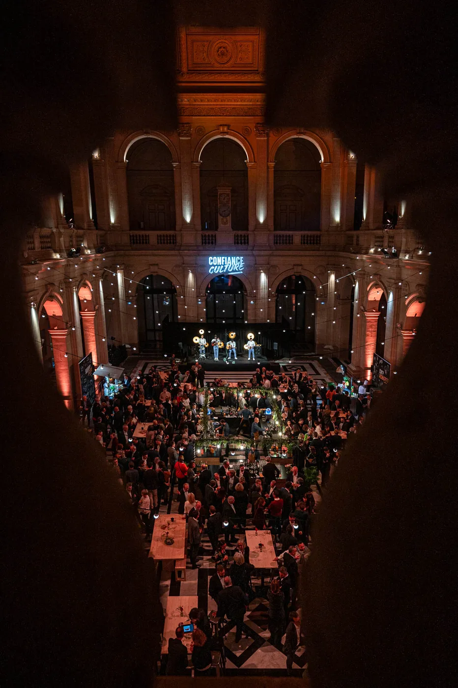 Vue plongeante d'une grande salle historique en convention, public dense, sc&egrave;ne illumin&eacute;e